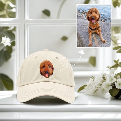 Beige cap with a dog's face embroidered on it, placed on a white surface with a blurred background.